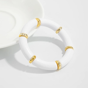Close-up of white resin bamboo-style bracelet segments with gold metal spacer rings