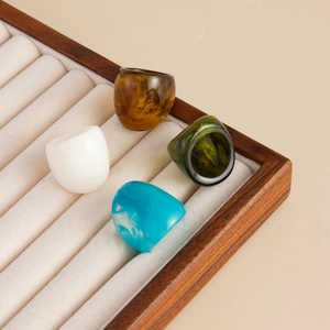Set of four minimalist resin rings in amber, white, and marble blue on a jewelry tray