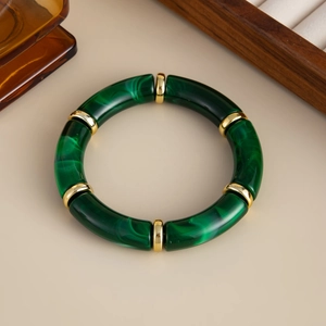 Nahaufnahme eines dunkelgrünen Bambusarmbandes aus Harz mit edlen goldenen Zwischenringen