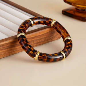 Close-up of tortoise shell acrylic links with gold metal rings on a wooden tray