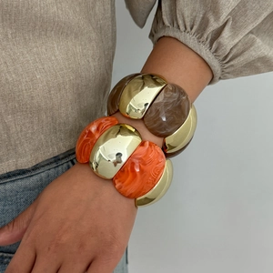 Detail of chunky amber resin and gold metal bangle set with marbled textures