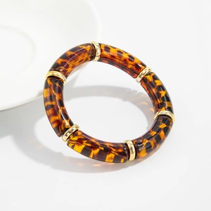 Detail of leopard print acrylic bangle with golden beads on a white ceramic plate