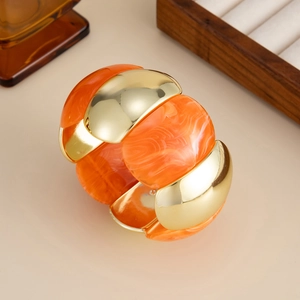 Macro shot of gold-plated metal and orange marble resin segments on an elastic bracelet
