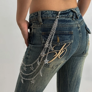 Detail of silver multi-layer punk pants chain with star charms and cross tassels on denim