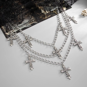 Detailed view of triple-layered silver chains with vintage gothic cross pendants on lace