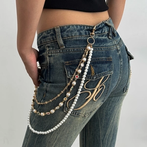 Dettaglio della catena per pantaloni dorata multistrato con perle e stelle colorate