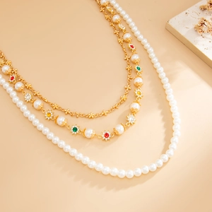 Dettaglio macro di collana a tre strati dorata con perle e pietre preziose colorate