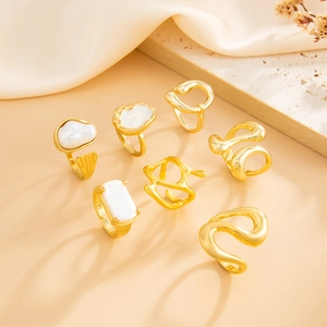 Close-up of gold baroque pearl ring set with irregular geometric metal bands on silk fabric
