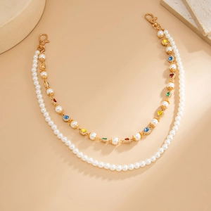 Dettaglio della catena di perle a doppio strato con strass colorati e chiusure a moschettone oro