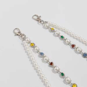 Dettaglio della tracolla a doppia catena con perle, cristalli colorati e moschettoni