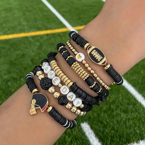 Macro shot of Game Day elastic bracelet set with football charms on a green field