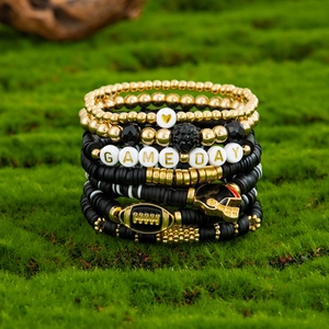 Close-up of beaded bracelet set with GAME DAY letters and Heishi beads on green moss
