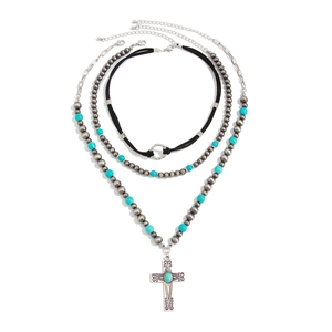 Close-up of bohemian layered necklaces with turquoise cross pendant and beaded detail