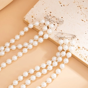 Detail of three-layer faux pearl tassel chains with silver safety pins on stone base