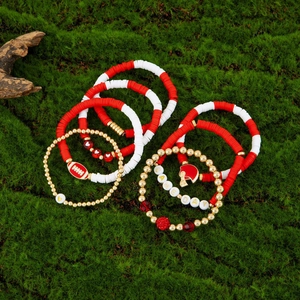 Close-up of Game Day beaded bracelet set with football charms on a mossy background