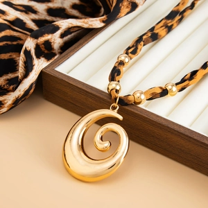 Detailed macro view of a large golden spiral heart pendant with leopard print fabric cord