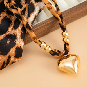 Close-up of golden heart pendant necklace with leopard print fabric cord and metal beads