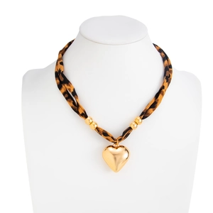 Close-up of leopard print fabric necklace with large gold metal heart pendant