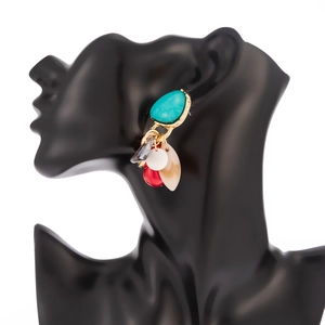 Details von Ethno-Ohrringen mit Türkis, roten Perlen und Blattanhänger am schwarzen Model