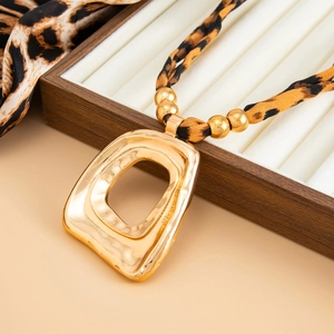 Detail of leopard print fabric necklace with gold hollow geometric heart pendant