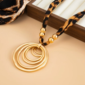 Detail of leopard print fabric necklace with gold layered concentric circle pendant