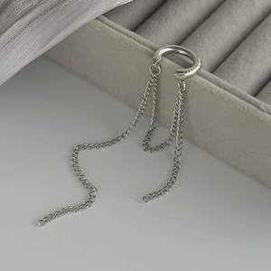Détail du bijou d'oreille argenté avec pompons à chaînes et anneau en forme de C