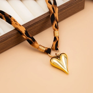 Close-up of leopard print fabric choker featuring a gold textured heart-shaped metal pendant