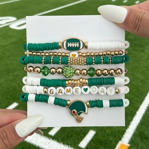 Close-up of 7-piece Game Day football beaded bracelet set on green grass background