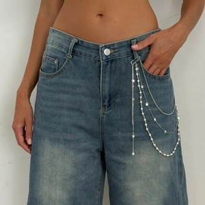 Close-up of layered silver waist chain with star charm and imitation pearls on denim