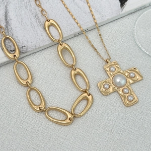 Detailaufnahme einer goldenen Kreuzkette mit Perlen auf einem Vogue-Magazin im Vintage-Stil