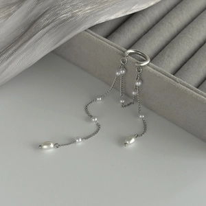 Détail d'un ear cuff argenté à pampilles de perles sur un coffret à bijoux gris