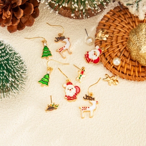 Close-up of Christmas themed drop earrings with reindeer, Santa, and tree elements