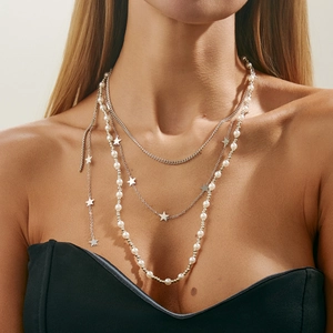 Close-up of layered silver chain with stars and pearls worn as a trendy accessory