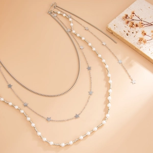 Multi-layer silver star and faux pearl body chain on a minimalist beige background