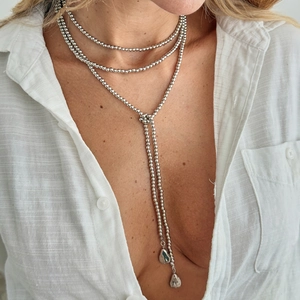 Detail van een zilveren kralenketting met meerdere lagen en Y-vormige waterdruppel hangers