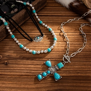 Detail of bohemian silver cross necklace with blue turquoise inlays on a rustic wooden base