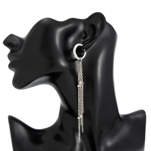 Vue latérale de longues boucles d'oreilles à pompons argentés sur un buste noir