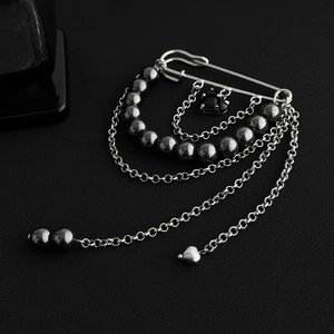 Close-up of gothic silver brooch with black heart pendant and layered tassel chains
