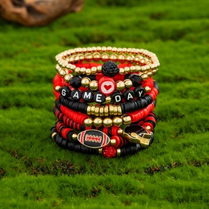 Detail of stacked Game Day beaded bracelets with football charms on green moss background