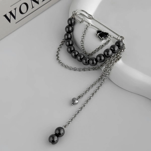 Close-up of safety pin brooch with black bead tassels and heart-shaped gemstone