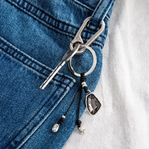 Close-up of stylish pants chain with heart acrylic charm and silver carabiner on jeans