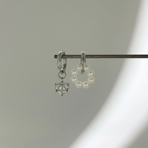 Détail de boucles d'oreilles asymétriques avec zircon cœur en argent et pendentif perles