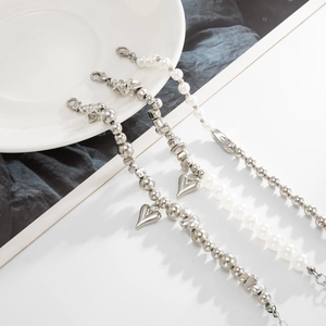 Detailaufnahme von Armbändern mit Herzanhänger und weißem Perlen-Set in Silber