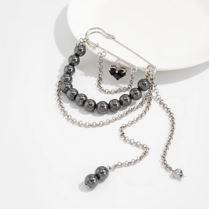 Detail of punk style silver safety pin brooch with heart pendant and layered chains