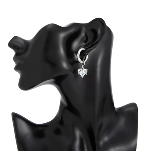 Détail de boucles d'oreilles créoles argentées avec pendentif cristal en forme de cœur