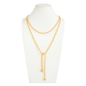 Gedetailleerd beeld van lange gouden kralenketting met hangers op een witte mannequin