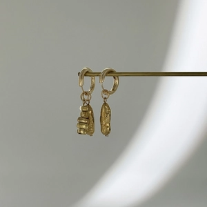 Vue détaillée de boucles d'oreilles dorées avec texture vintage irrégulière et asymétrie
