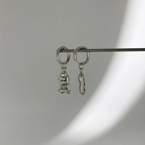 Vue détaillée de boucles d'oreilles créoles asymétriques argentées avec pendentif métal