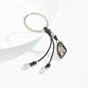Detailed macro of a faceted grey crystal pendant on a black woven cord keychain