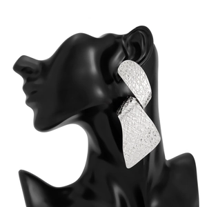 Detalle de pendientes plateados con textura arrugada en un maniquí negro